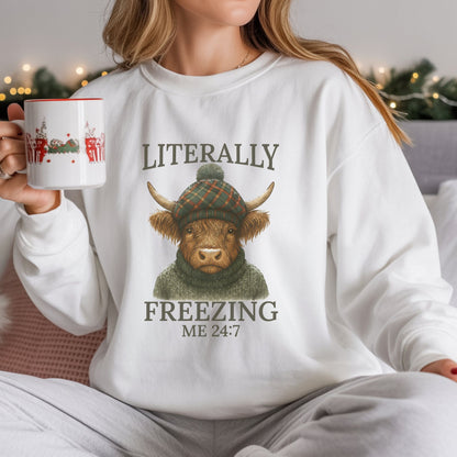 Person wearing a white sweatshirt with a Highland cow graphic and text, holding a mug.
