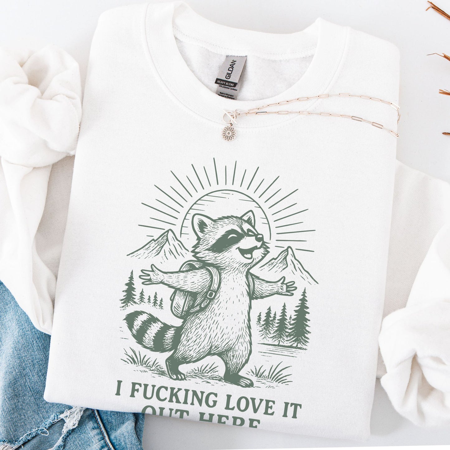 White sweatshirt with a raccoon graphic and text on a white background