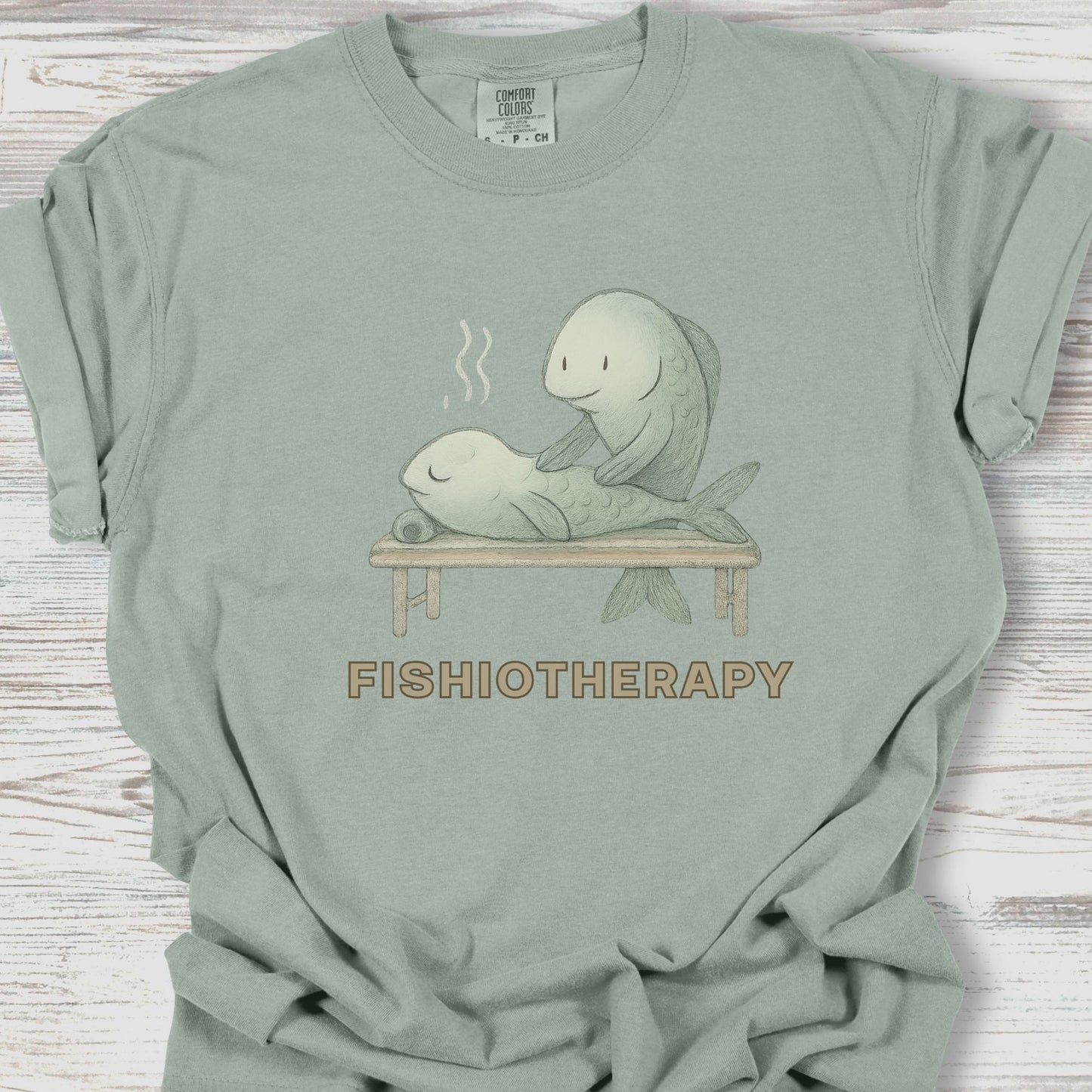 Sage green t-shirt with 'Fishiotherapy' graphic on a wooden surface