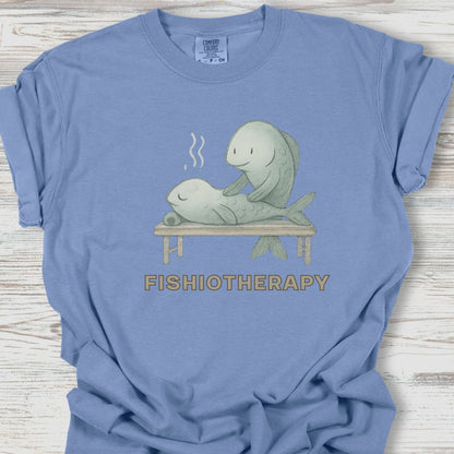 Blue t-shirt with 'Fishiotherapy' graphic featuring fish and a seal on a wooden surface
