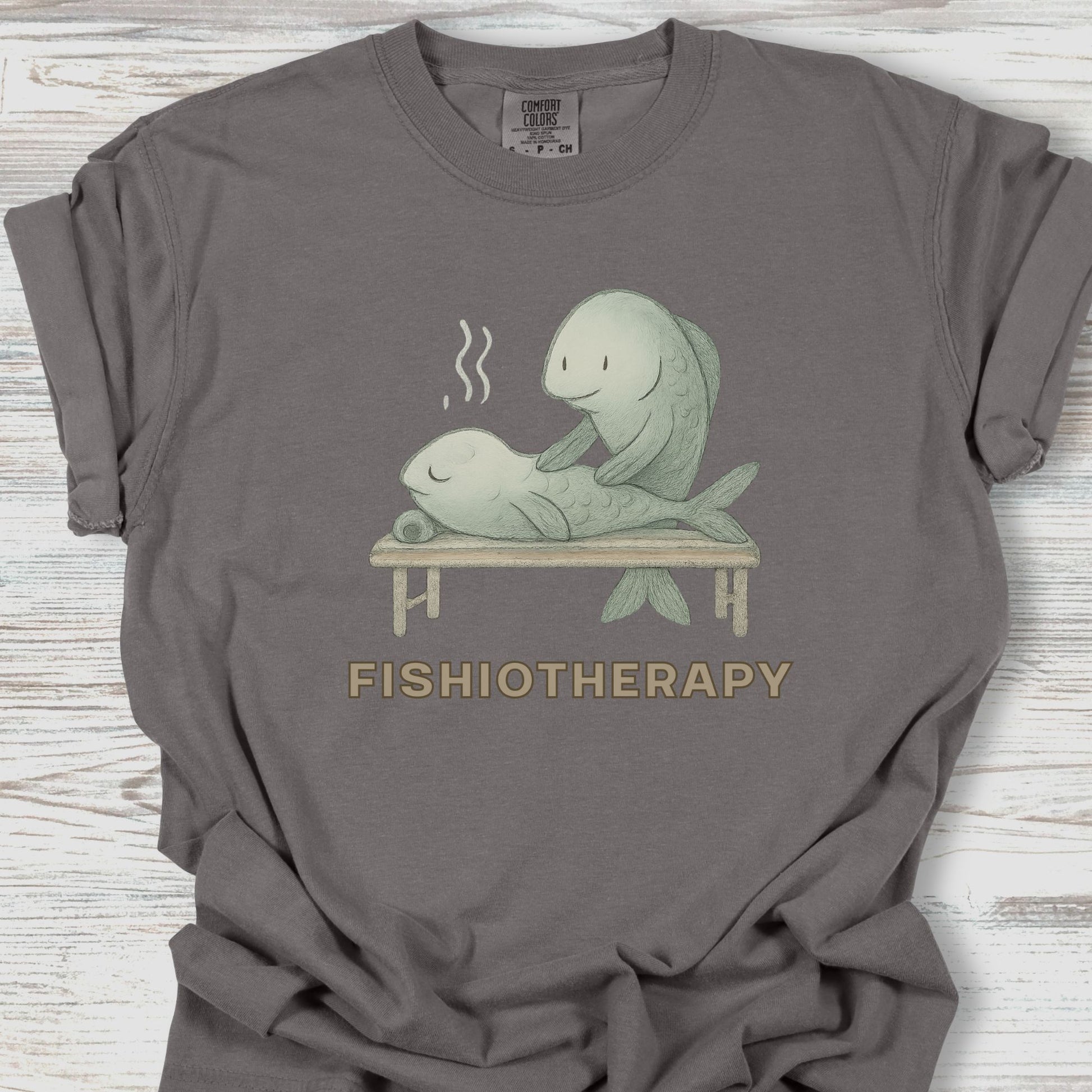Gray t-shirt with 'Fishiotherapy' graphic on a wooden surface