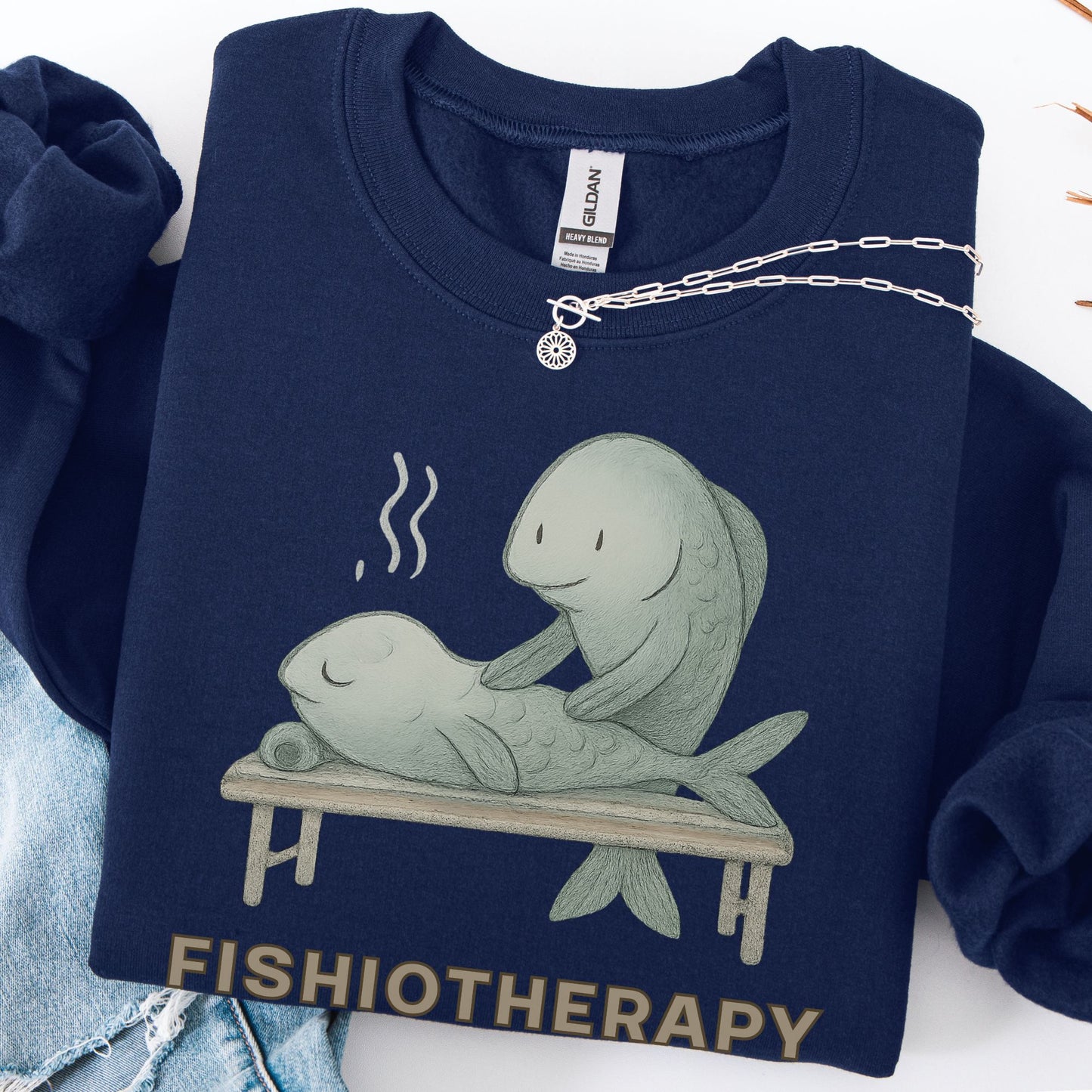 Navy blue sweatshirt with 'Fishiotherapy' design featuring two fish on a table, displayed with a necklace.