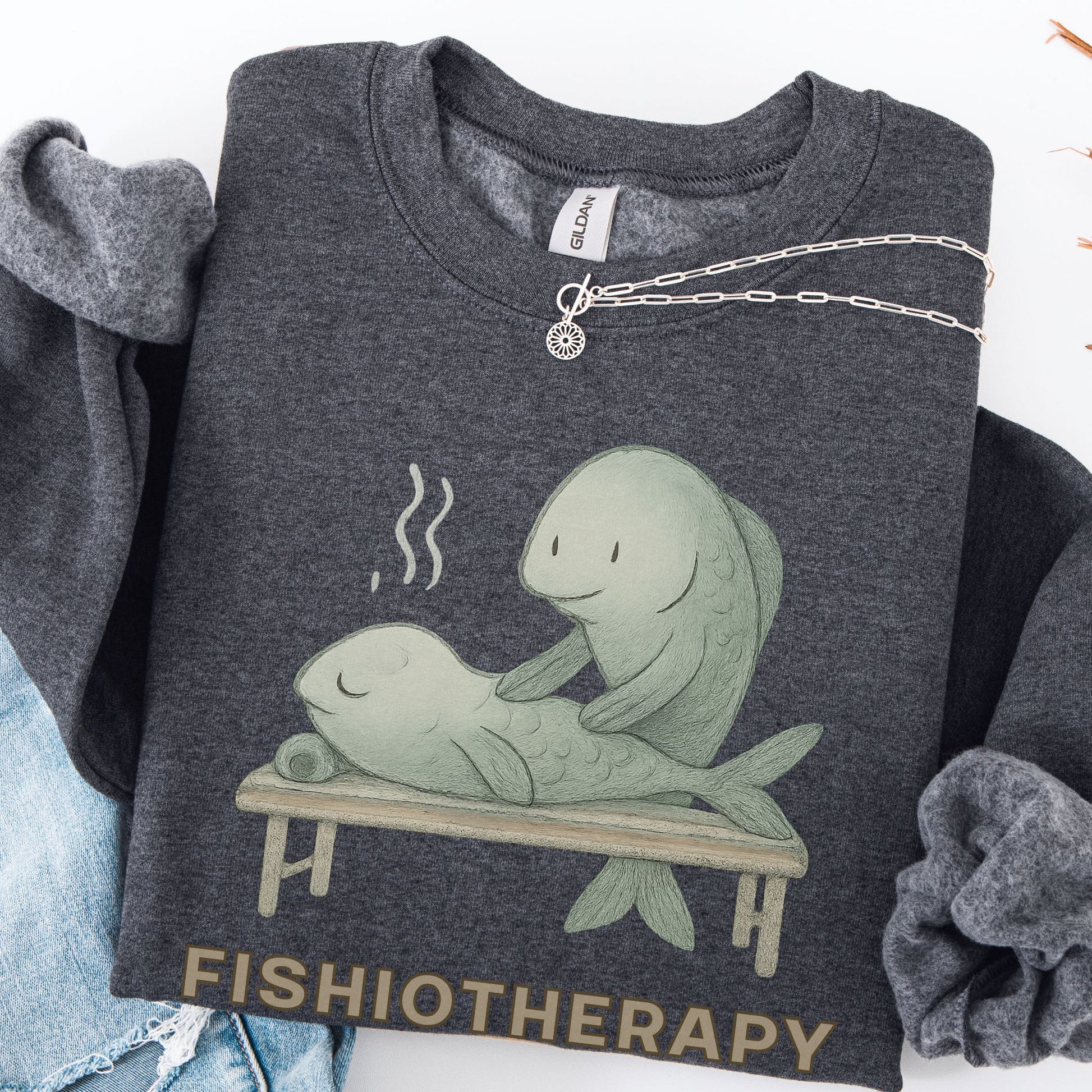 Dark gray sweatshirt with 'Fishiotherapy' graphic and text, displayed with denim jeans and a necklace.