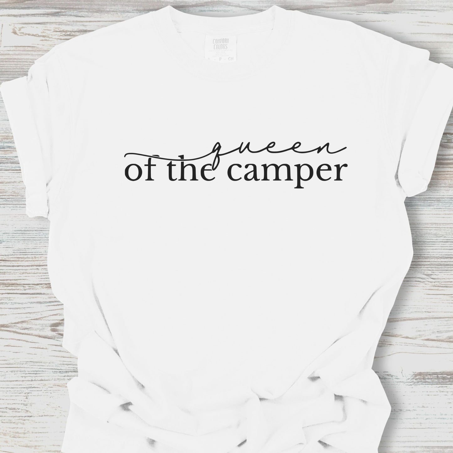 White t-shirt with 'Queen of the Camper' text on a wooden surface