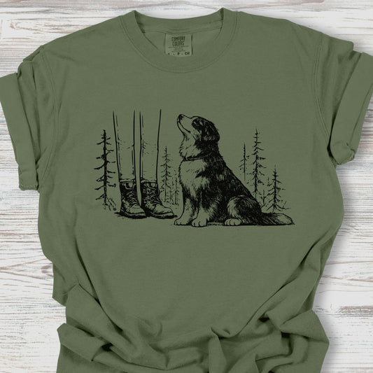 Green t-shirt with a dog and forest design on a wooden surface