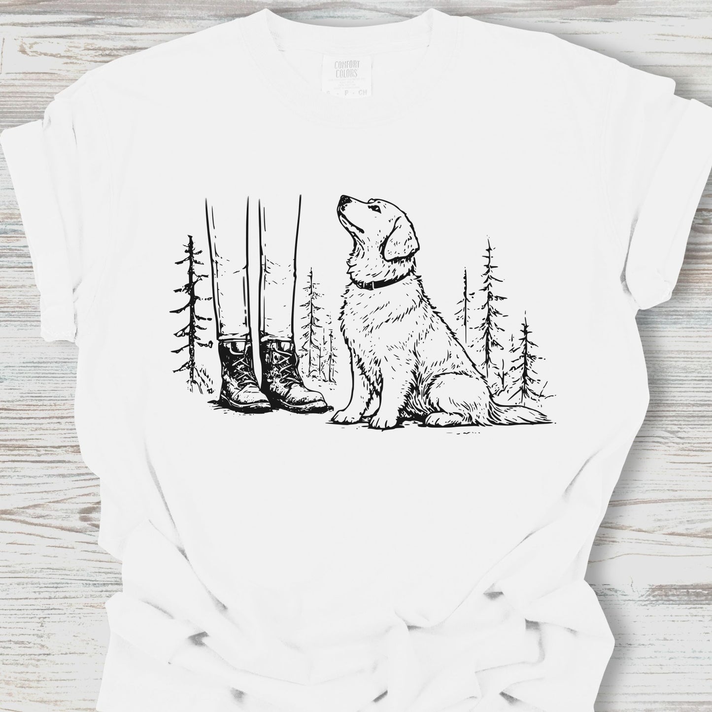 White t-shirt with a graphic of a dog, boots, and trees on a wooden surface