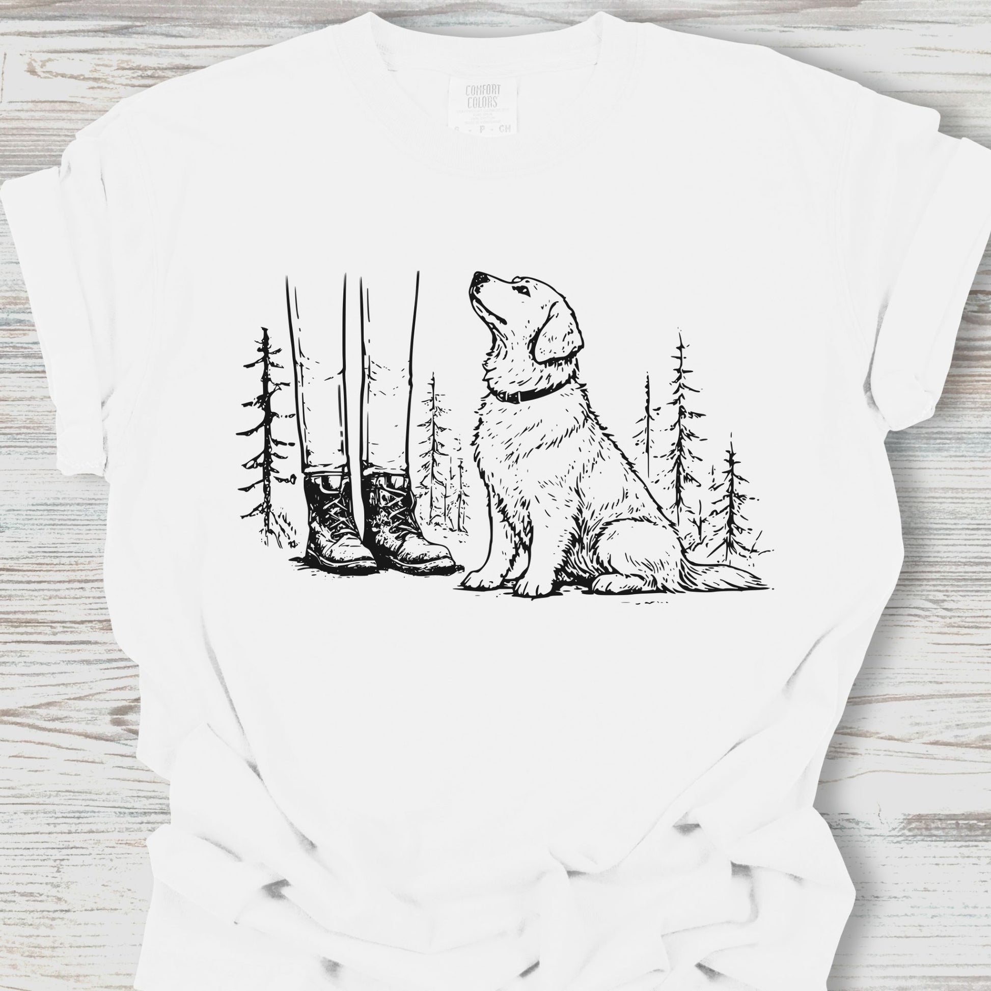 White t-shirt with a graphic of a dog, boots, and trees on a wooden surface