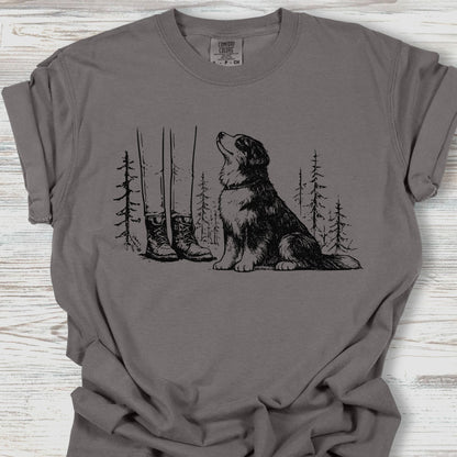 Gray t-shirt with a graphic of a dog, boots, and trees on a wooden surface