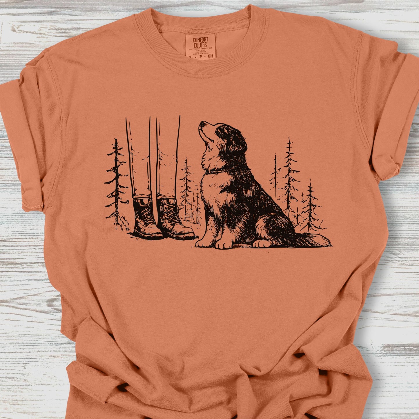 Coral t-shirt with a dog and forest design on a wooden surface