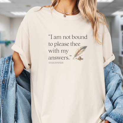 Model wears an ivory t-shirt with black lettering that reads, I am not bound to please thee with my answers.  There is the image of a feather quill and ink jar next to the lettering.  This makes a great gift for dark academia enthusiasts, book lovers and teachers.
