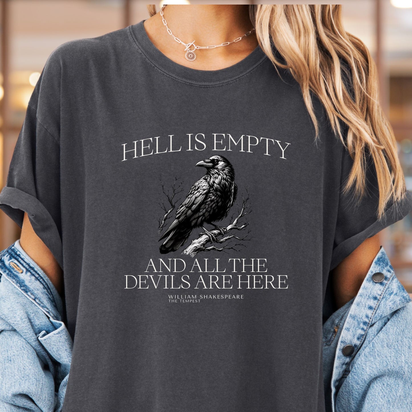 Model wears a grey t-shirt called pepper with the image of a raven perched on a branch with white lettering that reads Hell is empty and all the devils are here William Shakespeare The Tempest.