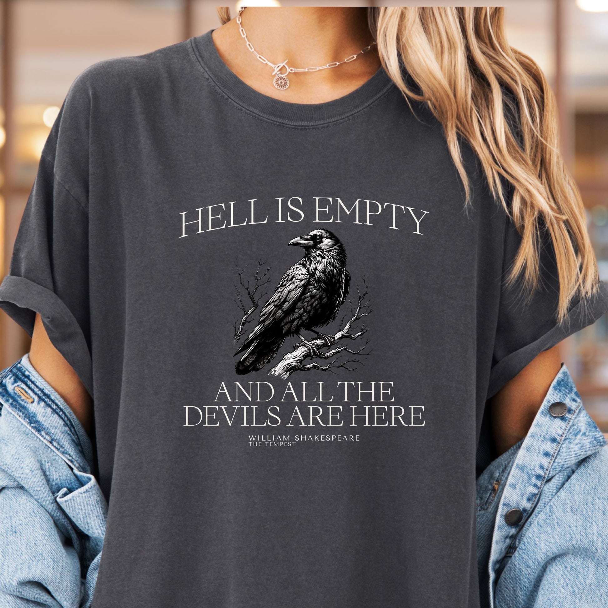 Model wears a grey t-shirt called pepper with the image of a raven perched on a branch with white lettering that reads Hell is empty and all the devils are here William Shakespeare The Tempest.