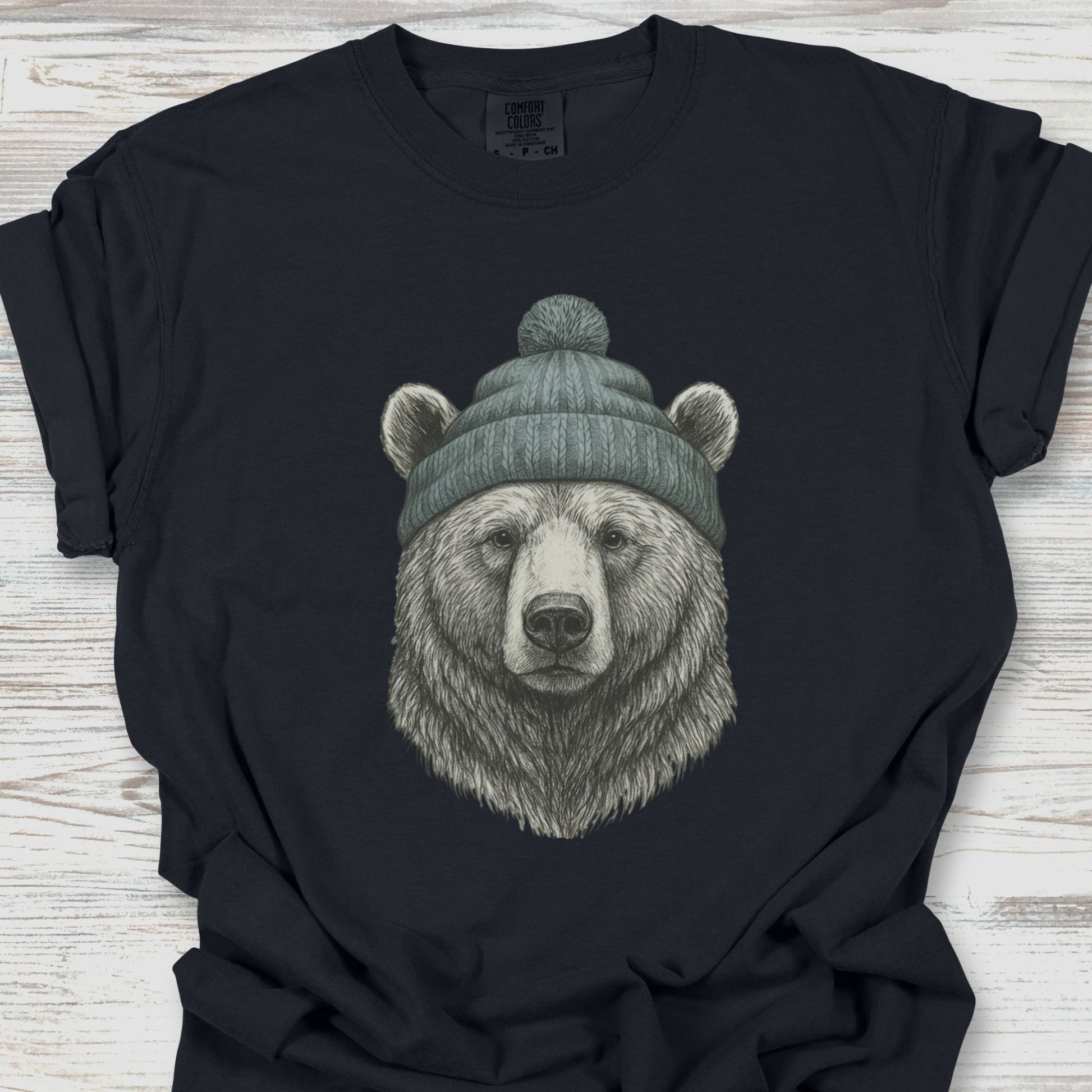 Black t-shirt with a bear wearing a beanie on a wooden surface
