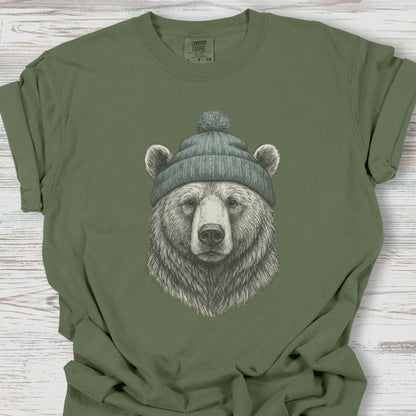 Green t-shirt with a bear wearing a beanie graphic on a wooden surface