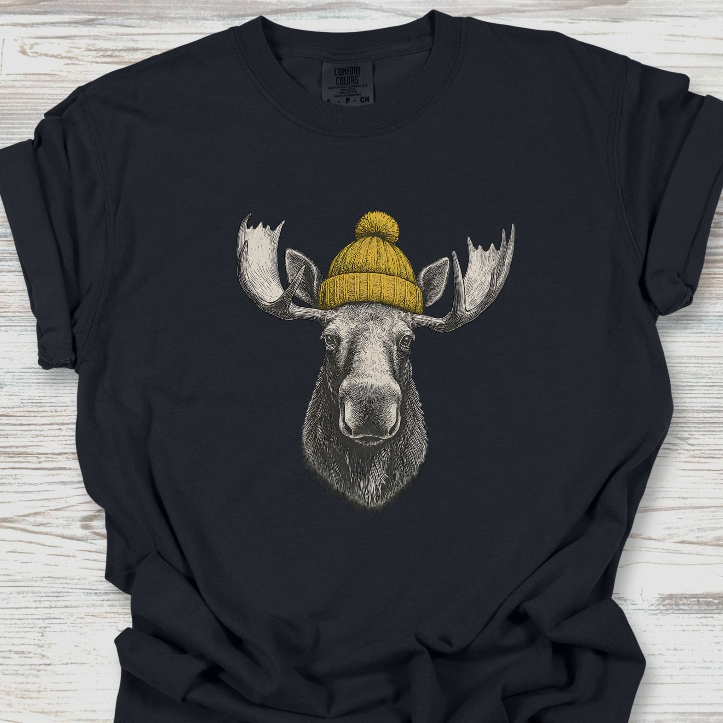 Black t-shirt with a moose wearing a yellow beanie on a wooden surface