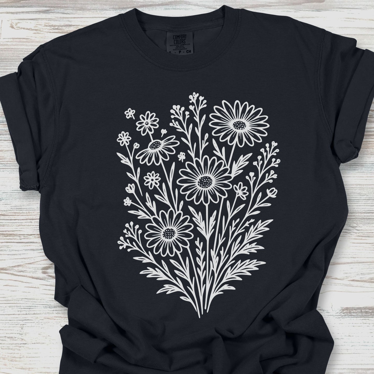 Black t-shirt with white floral design on a wooden surface