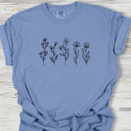 Blue t-shirt with black floral designs on a wooden surface