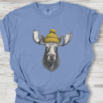 Blue t-shirt with a moose wearing a yellow beanie on a wooden surface
