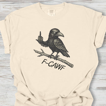 Beige t-shirt with a graphic of a crow and 'F-CAWF' text on a wooden surface