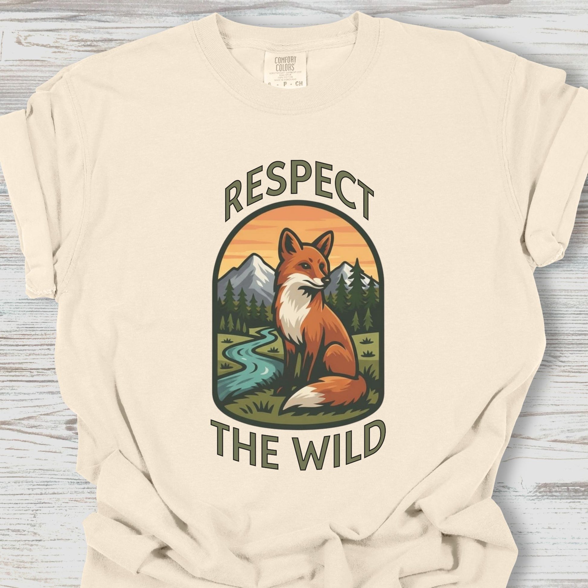 Beige t-shirt with a fox graphic and 'Respect the Wild' text on a wooden surface