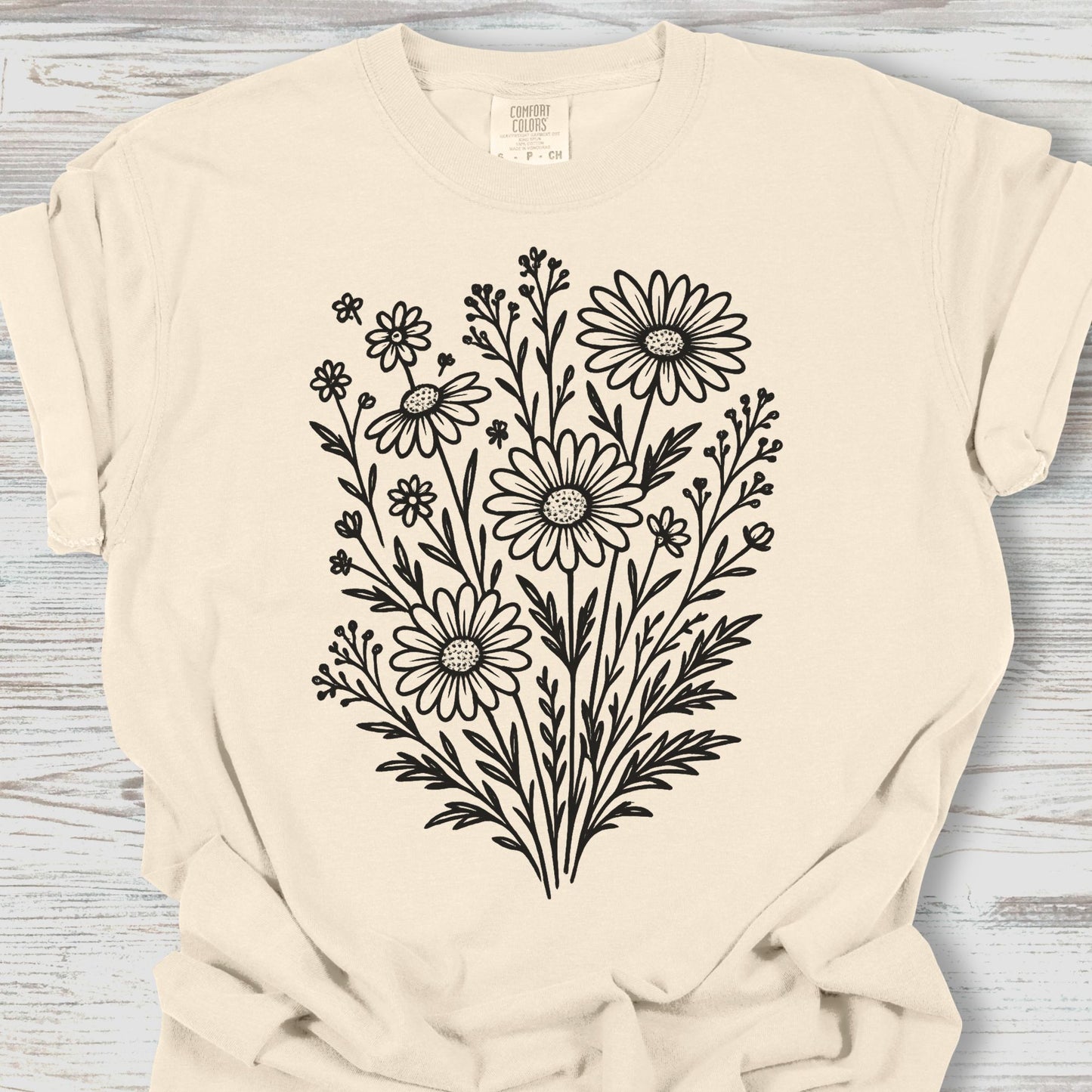 Beige t-shirt with black floral design on a wooden surface