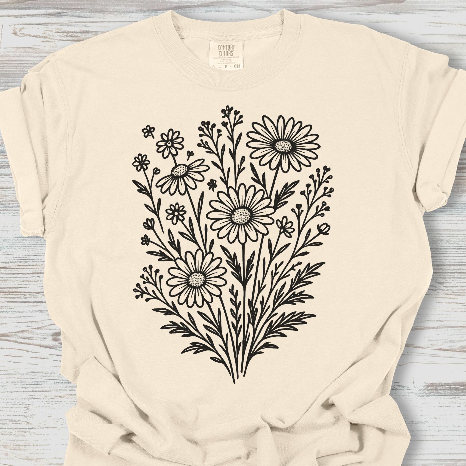 Beige t-shirt with black floral design on a wooden surface