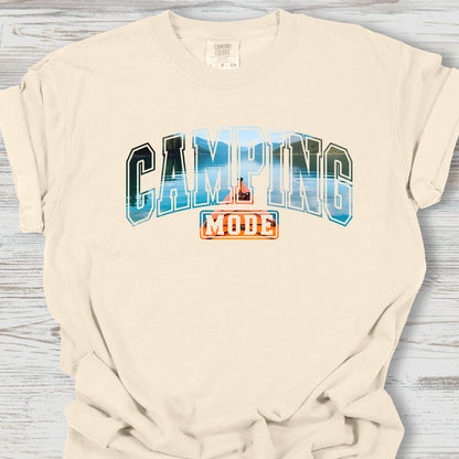 Beige t-shirt with 'Camping Mode' graphic on a wooden surface