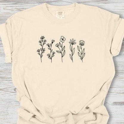 Beige t-shirt with black floral designs on a wooden surface