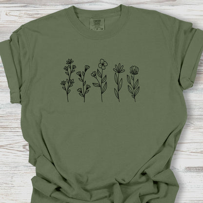 Green t-shirt with black floral designs on a wooden surface