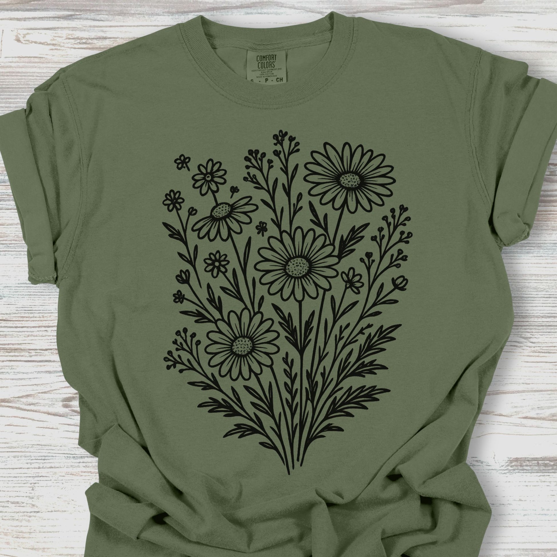 Green t-shirt with black floral design on a wooden surface