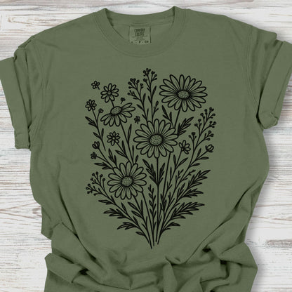 Green t-shirt with black floral design on a wooden surface