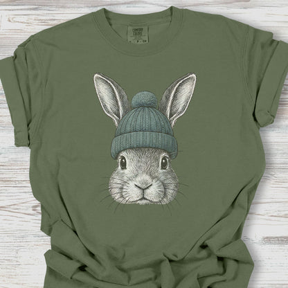 Green t-shirt with a rabbit wearing a blue beanie on a wooden surface