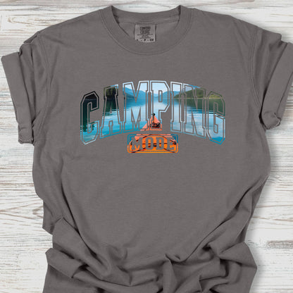 Gray t-shirt with 'Camping' graphic design on a wooden surface
