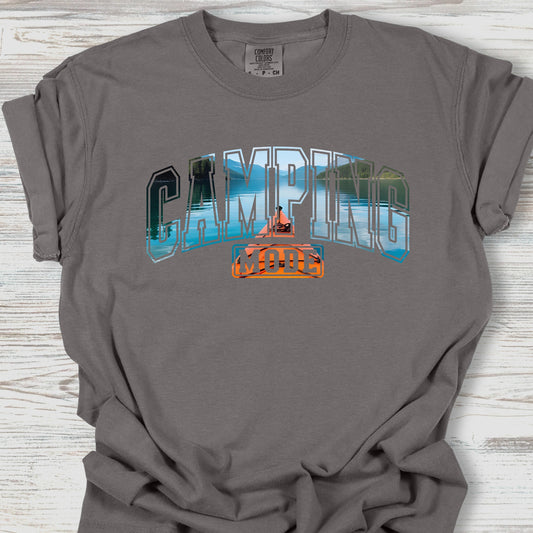 Gray t-shirt with 'Camping' graphic design on a wooden surface