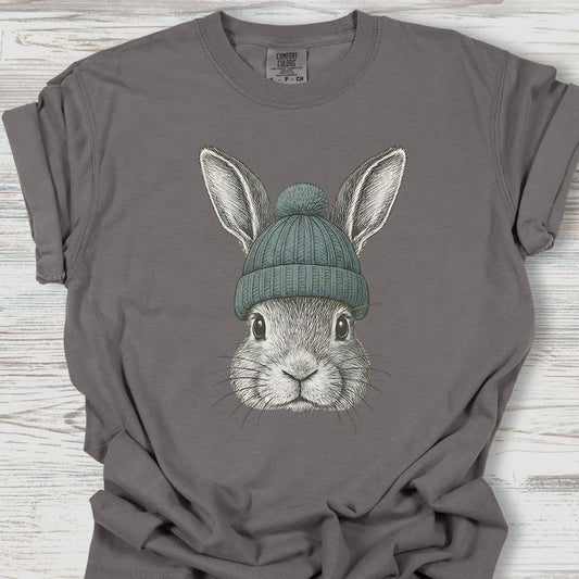 Gray t-shirt with a graphic of a rabbit wearing a green beanie on a wooden surface