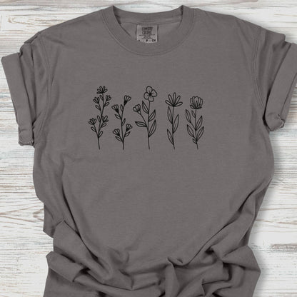 Gray t-shirt with black floral designs on a wooden surface