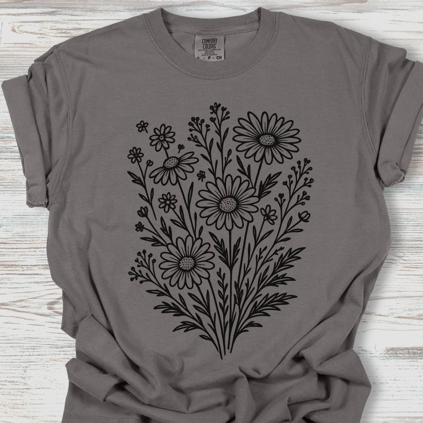 Gray t-shirt with black floral design on a wooden surface