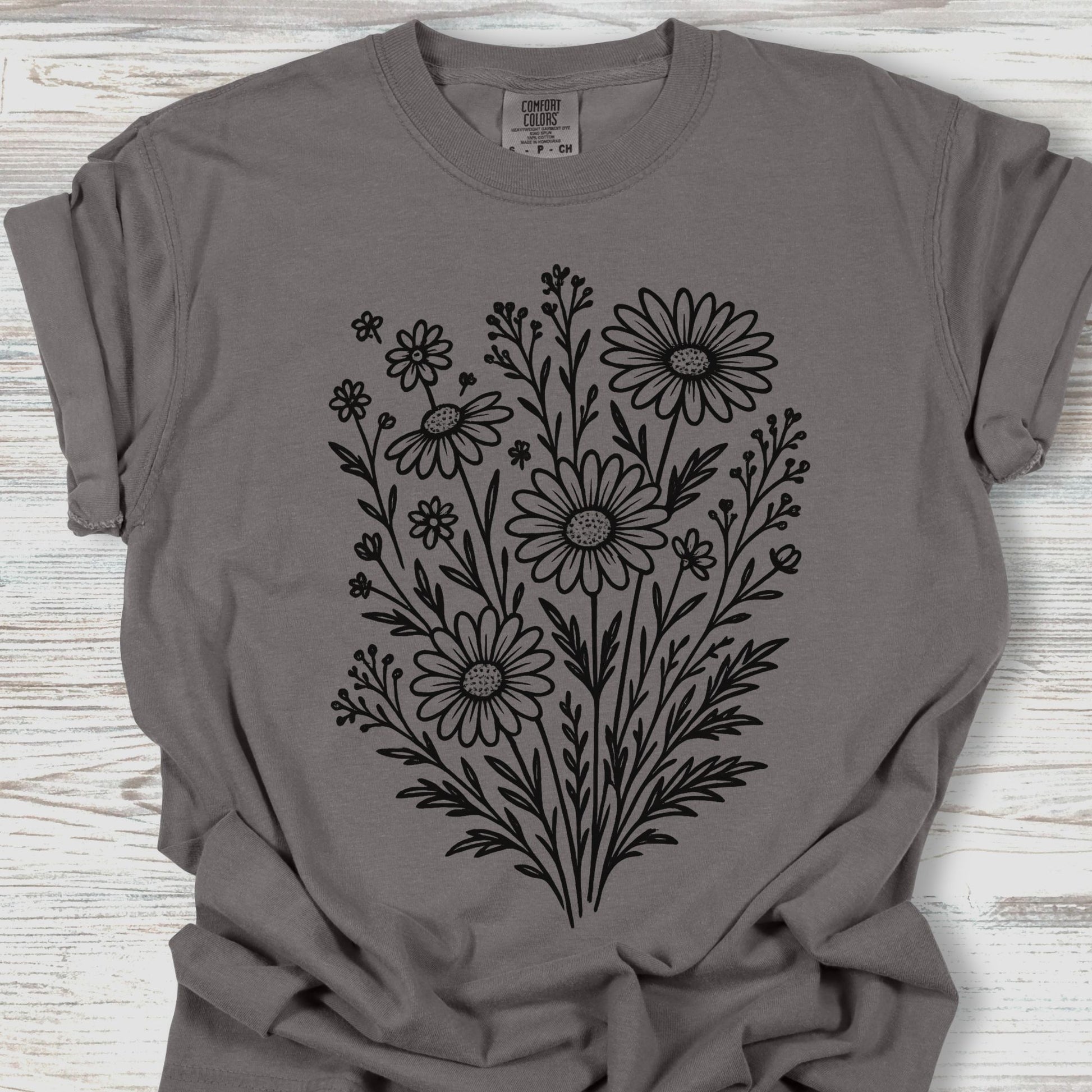 Gray t-shirt with black floral design on a wooden surface