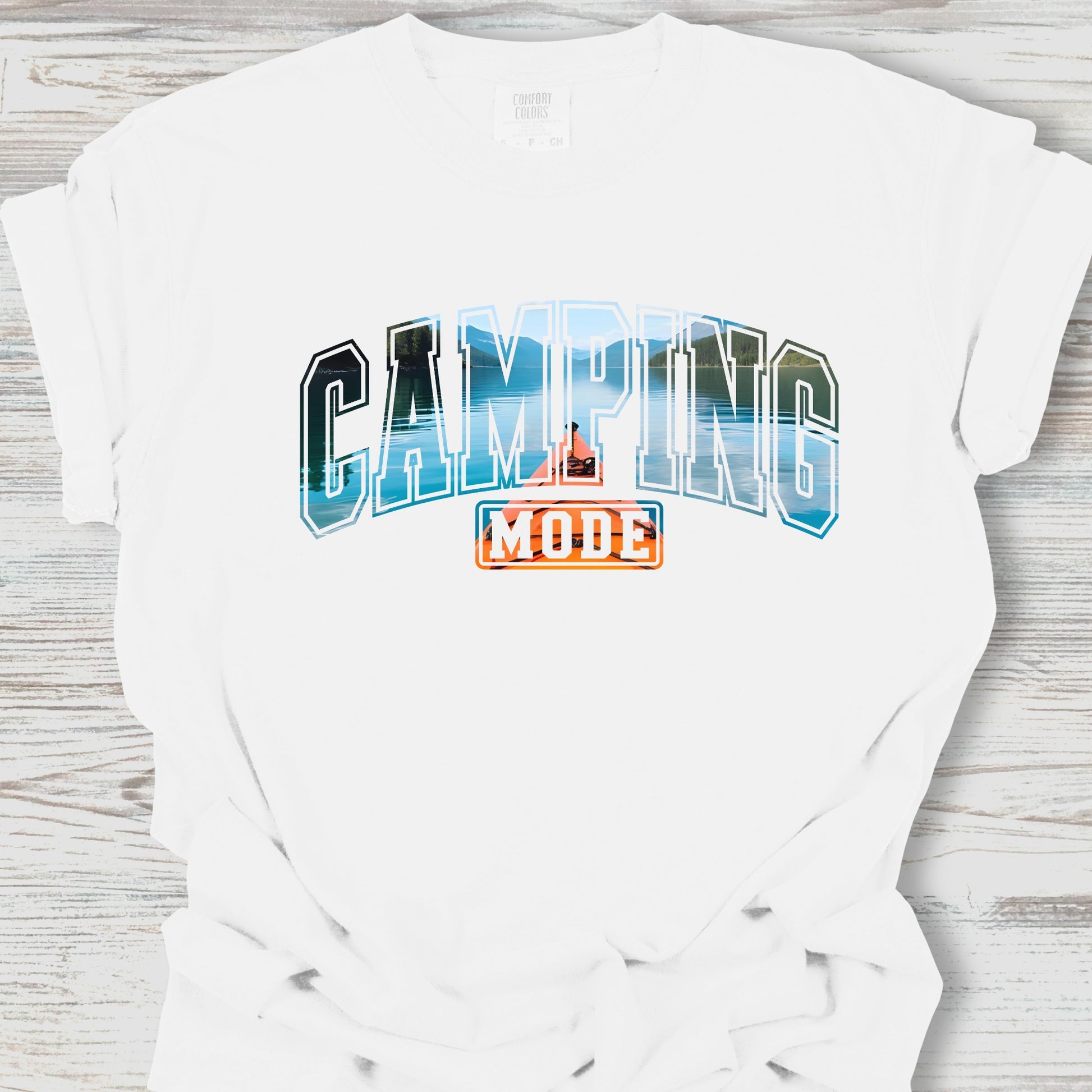White t-shirt with 'Camping Mode' graphic design on a wooden surface