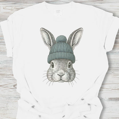 White t-shirt with a graphic of a rabbit wearing a green beanie on a wooden surface