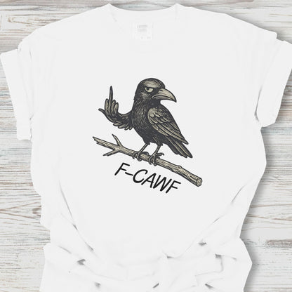 White t-shirt with a black crow illustration and 'F-CAWF' text on a wooden surface