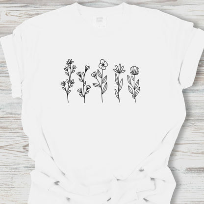 White t-shirt with black floral designs on a wooden surface