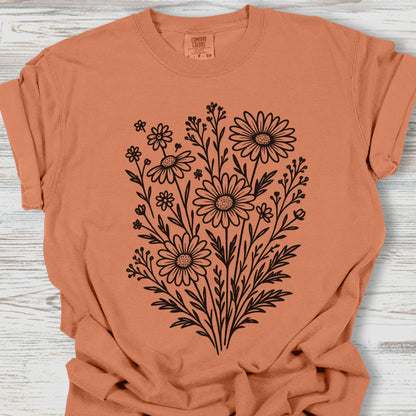 Coral t-shirt with black floral design on a wooden surface