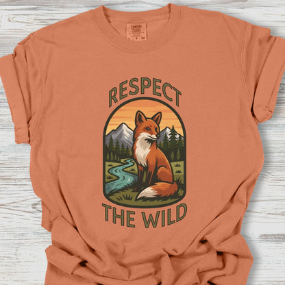 Orange t-shirt with a fox graphic and 'Respect the Wild' text on a wooden surface