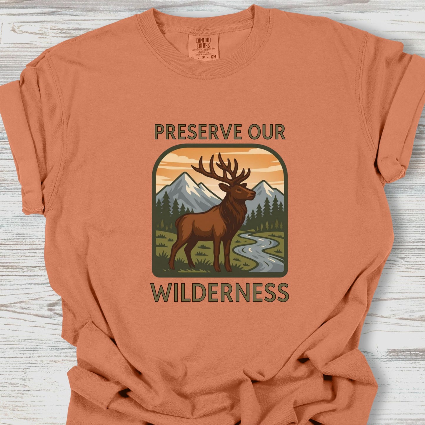 Coral t-shirt with a graphic of a deer and mountains, featuring the text 'Preserve Our Wilderness'.