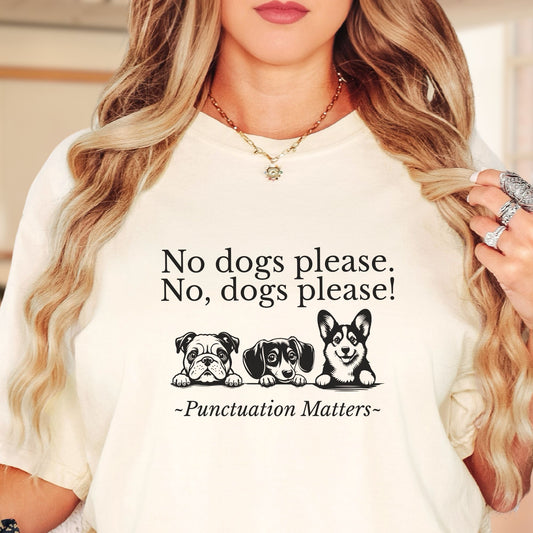 Model wears an ivory colored  tshirt with black lettering that reads 1sh line:  no dogs please .2nd line:  No, dogs please!, 3rd Line: 
 punctuation matters.  There is a picture of three cute dogs between the second and third lines of text.