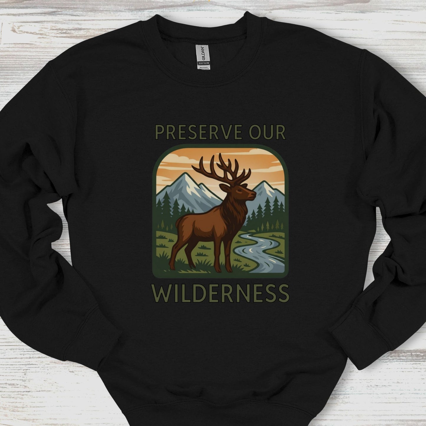 Black sweatshirt with a graphic of a deer and mountains and 'Preserve Our Wilderness' text on a wooden surface.
