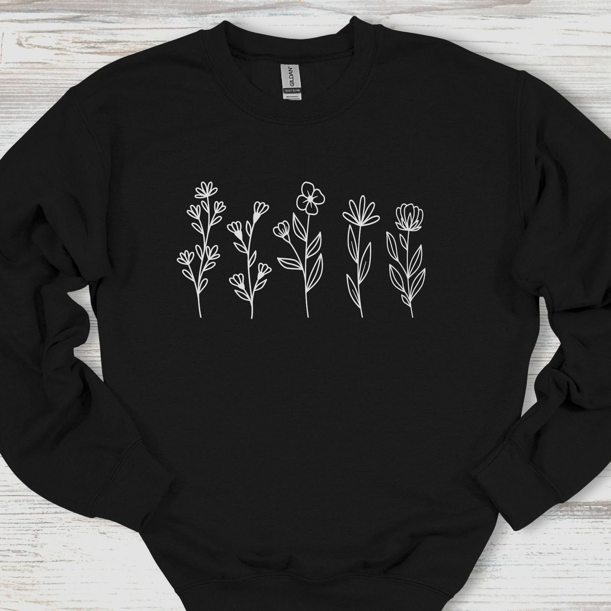 Black sweatshirt with white floral designs on a wooden surface