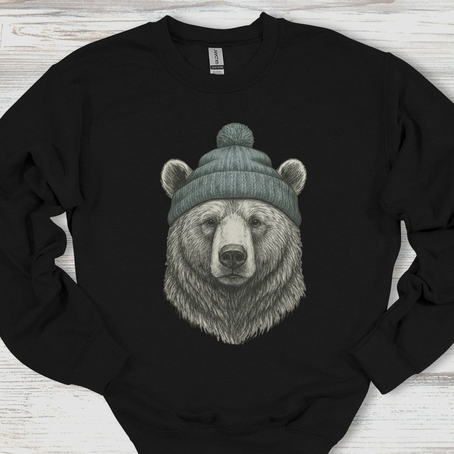 Black sweatshirt with a bear wearing a beanie on a wooden surface