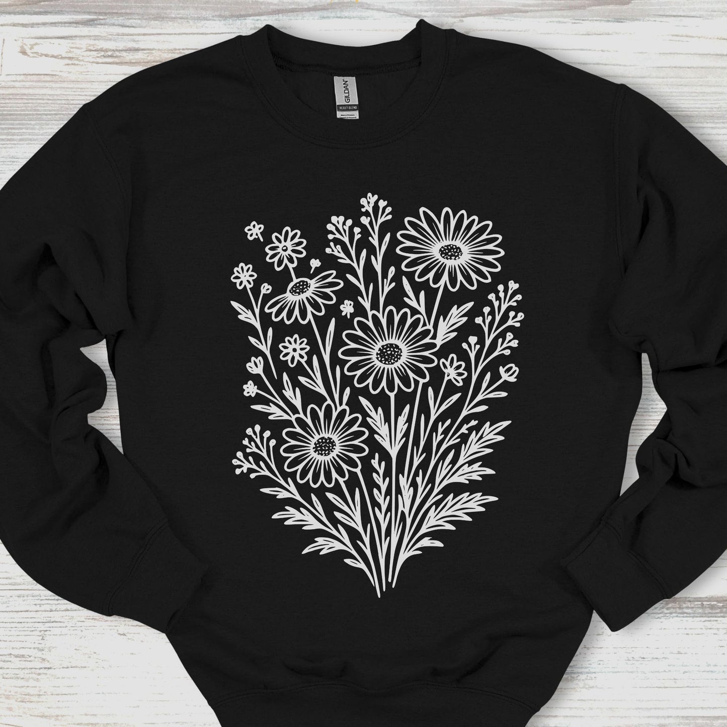 Black sweatshirt with white floral design on a wooden surface
